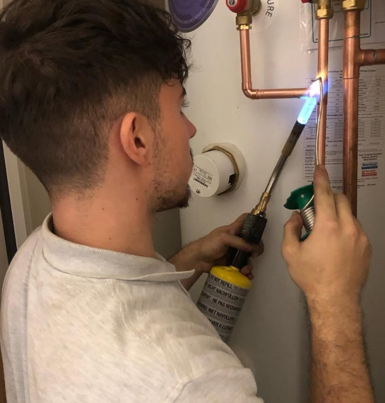 Engineer soldering copper pipework during a hot water cylinder replacement