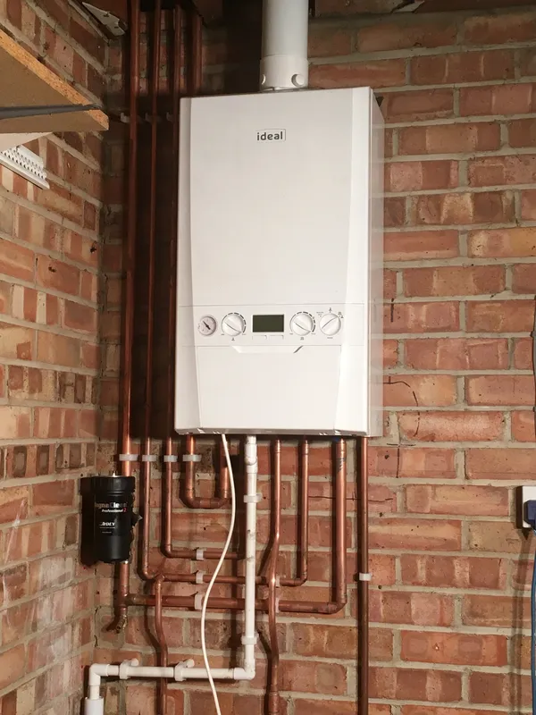 Newly installed Ideal gas boiler on a brick wall with neat copper pipework and isolation valves