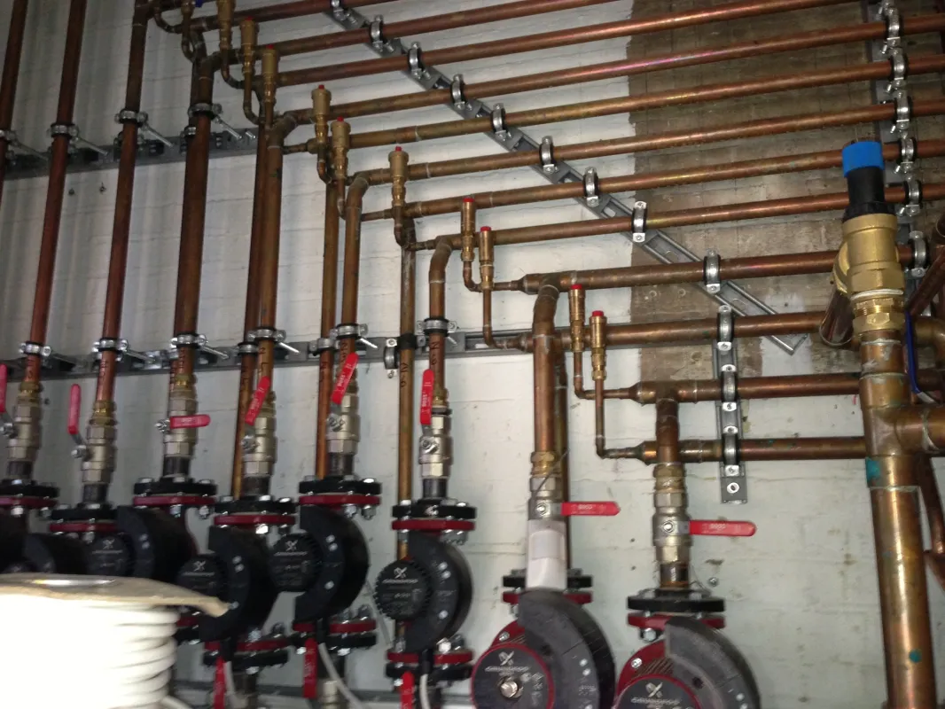 Vertical copper heating pipes with valves and pumps in a professionally finished install