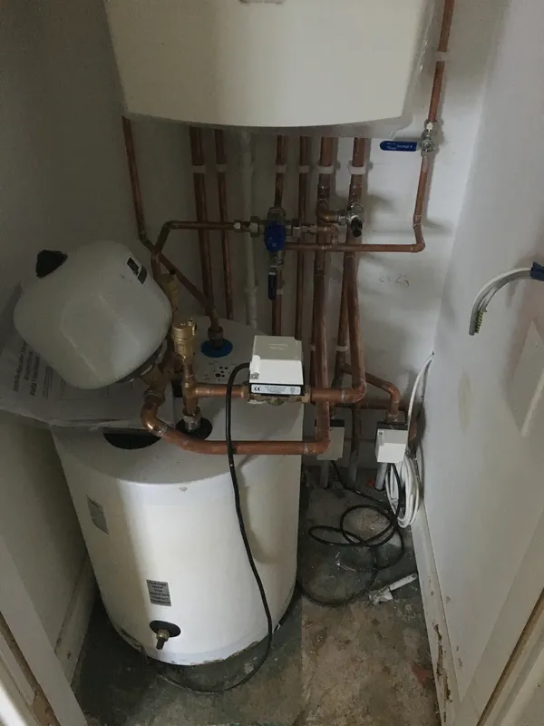 New unvented hot water cylinder and expansion vessel being fitted in an airing cupboard