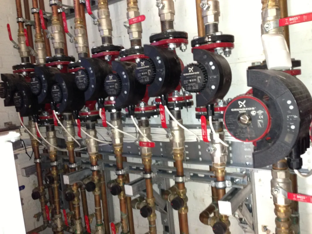 Row of Grundfos circulating pumps fitted to copper pipework with red isolation valves