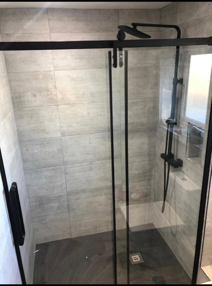 Sliding matt black framed shower enclosure with grey tiling, rainfall head and thermostatic shower valve