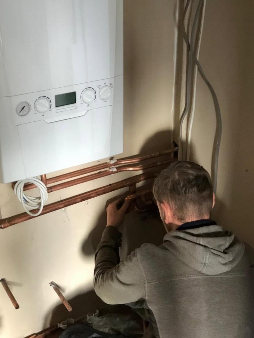 Engineer completing boiler pipework connections during a boiler replacement