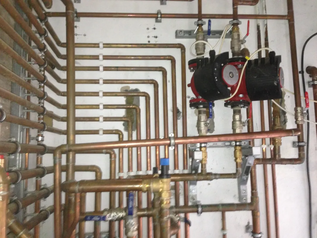 Neatly grouped copper heating pipework with twin Grundfos pumps after installation