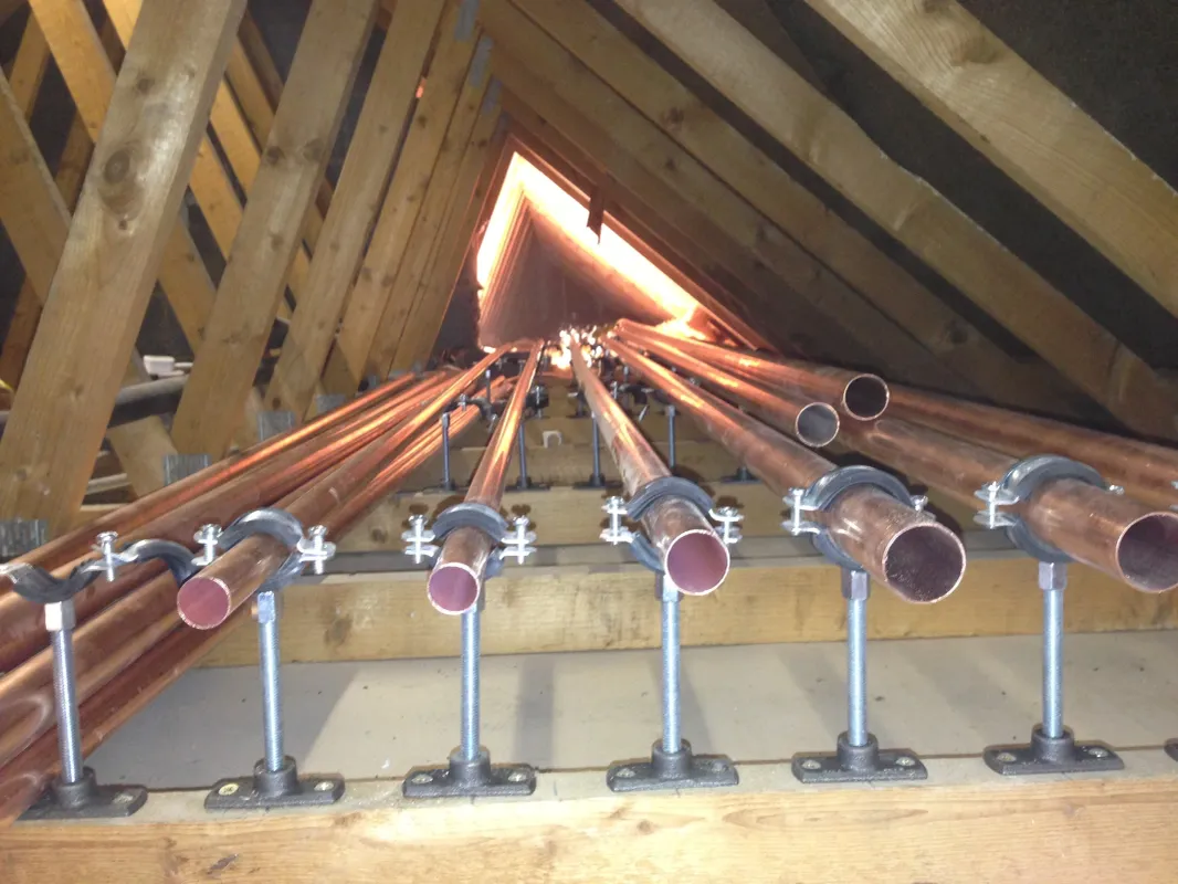 Copper heating pipework being run through loft rafters during a central heating installation
