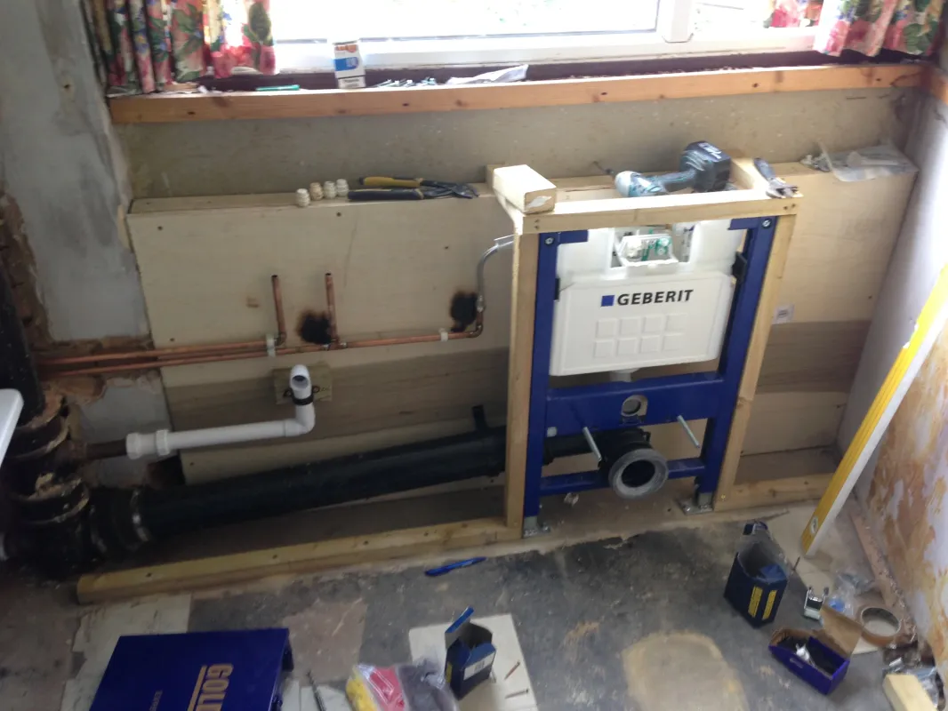 First-fix bathroom pipework and a concealed cistern frame set into the wall before tiling